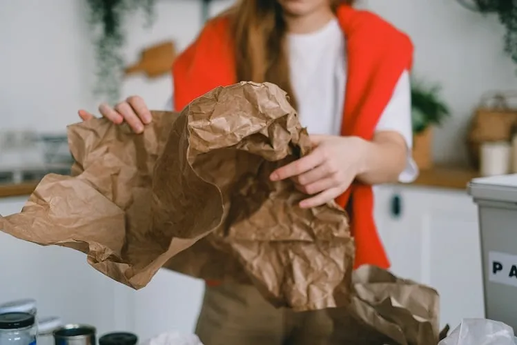 Osoba wyrzuca papier do pakowania